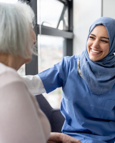 Muslim nurse talking to a senior patient at the hospital and smiling - healthcare and medicine concepts